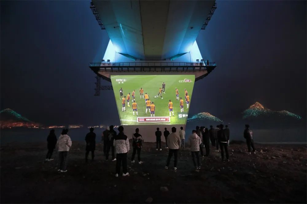 长江边看“世界杯”   李亚隆 摄2022年11月27日，湖北宜昌夷陵长江大桥露天电影大屏前，一群年轻人就着冬日的江风，观看2022卡塔尔世界杯直播。.jpg
